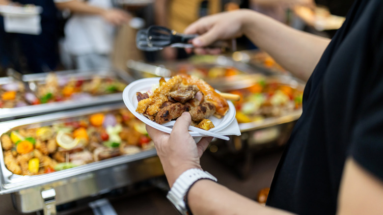 person holds a plate loaded with flavorful food