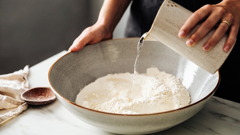 Pouring water into bowl of flour