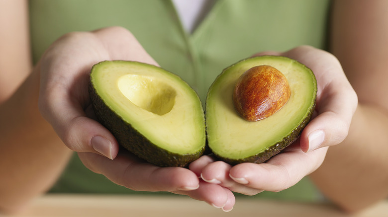 holding avocado cut in half