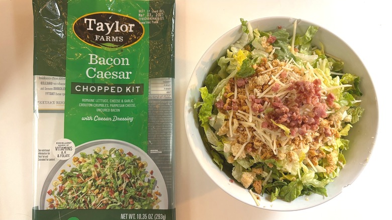 Taylor Farms Bacon Caesar Chopped Kit in white bowl next to package on white table