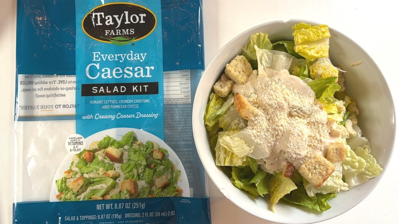 Taylor Farms Everyday Caesar Salad Kit in white bowl next to package on white table