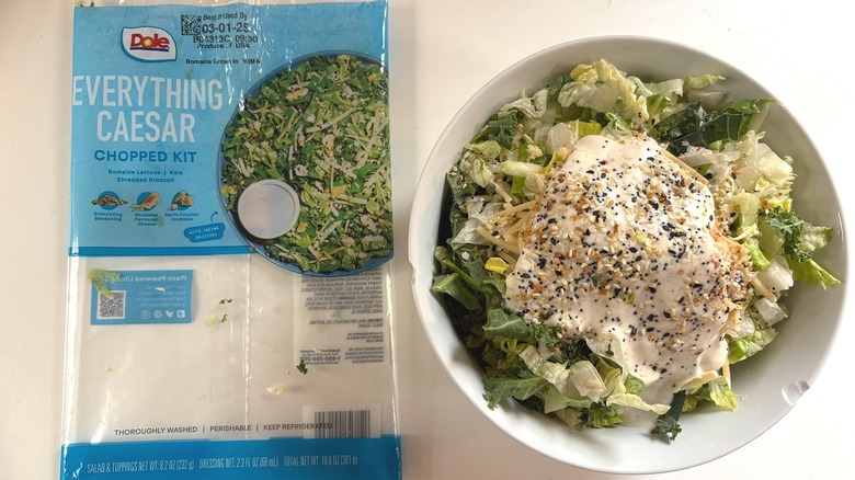 Dole Everything Caesar Chopped Salad Kit in white bowl next to package on white table