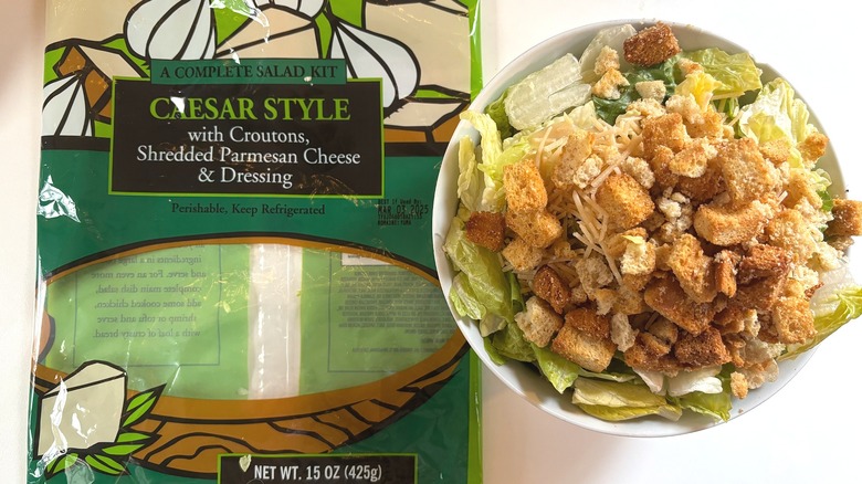 Trader Joe's Complete Caesar Style Salad Kit in white bowl next to package on white table