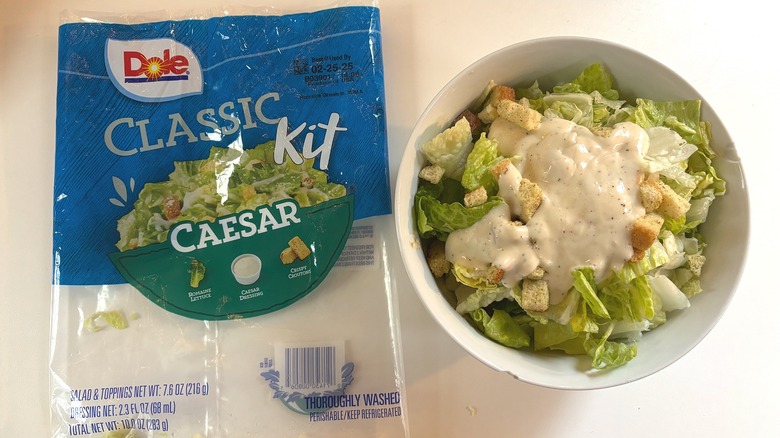 Dole Classic Caesar Salad kit in white bowl next to package on white table