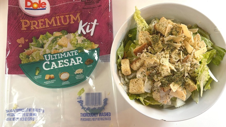 Dole Premium Ultimate Caesar Salad Kit in white bowl next to package on white table