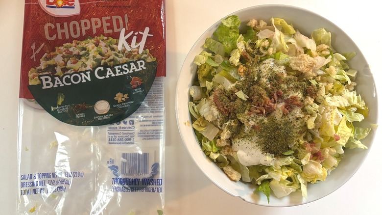 Dole Chopped Bacon Caesar Kit in white bowl next to package on white table