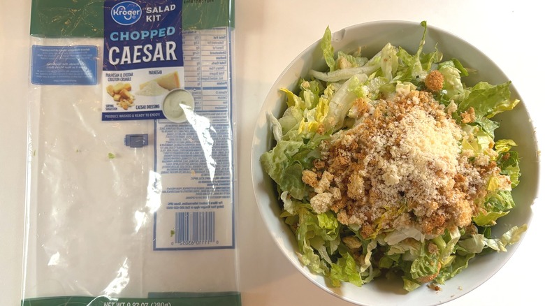 Kroger Chopped Caesar Salad Kit in white bowl next to package on white table