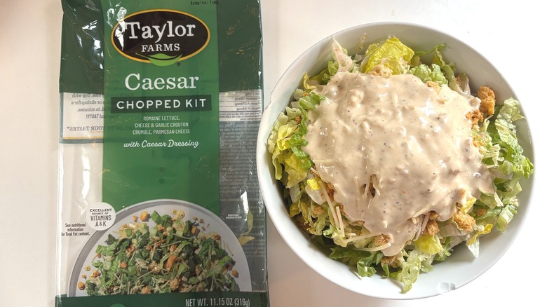 Taylor Farms Caesar Chopped Kit in white bowl next to package on white table