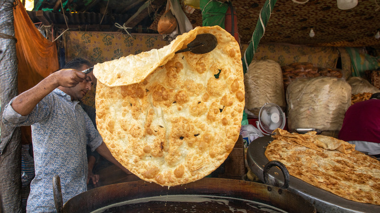 man lifting flat bread from oil