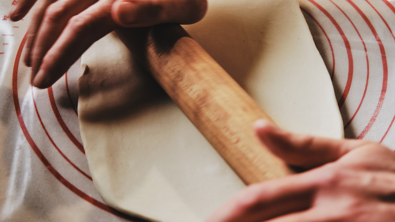 Rolling pie dough on mat