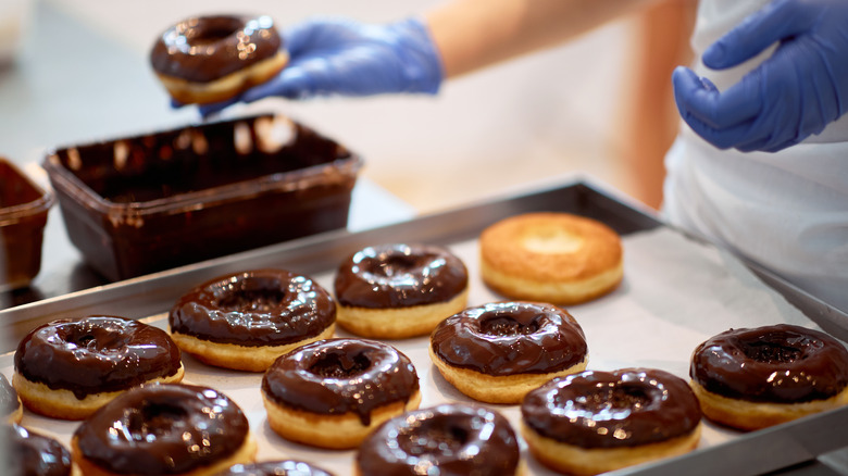 Person glazing donuts by hand