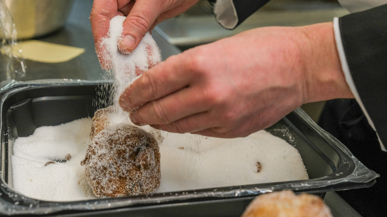 Adding granulated sugar to donuts