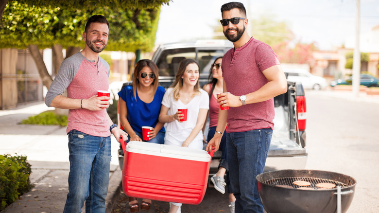 People carrying cooler at tailgate