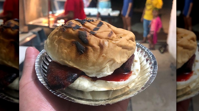 Burger on metal tray in hand