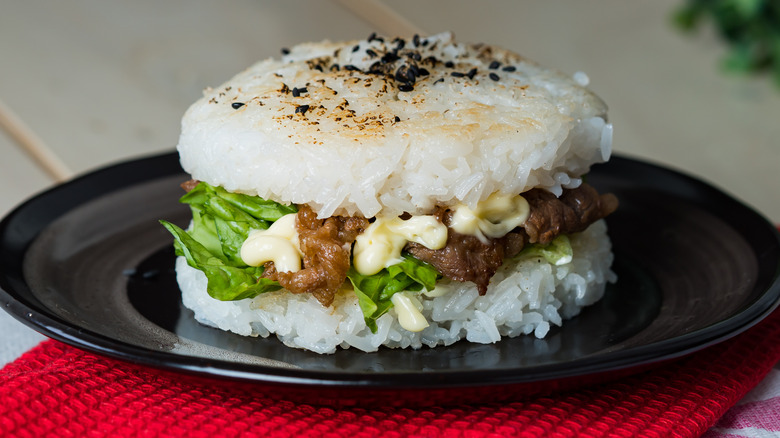 Burger with rice patties on black plate 