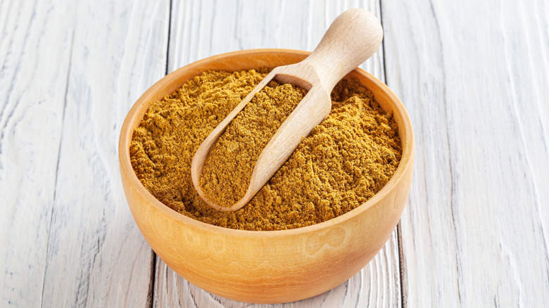 Curry powder on wooden spoon and bowl