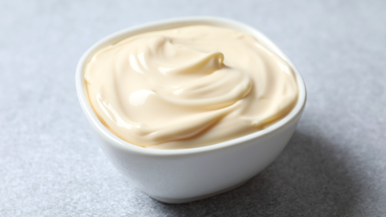 Bowl of mayonnaise on grey background