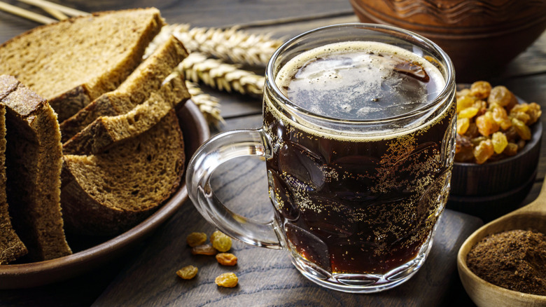 mug of kvass next to a small dish of raisins and plate of bread