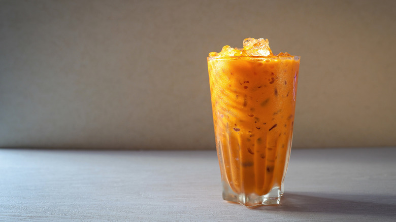 Glass of Thai iced tea against plain background