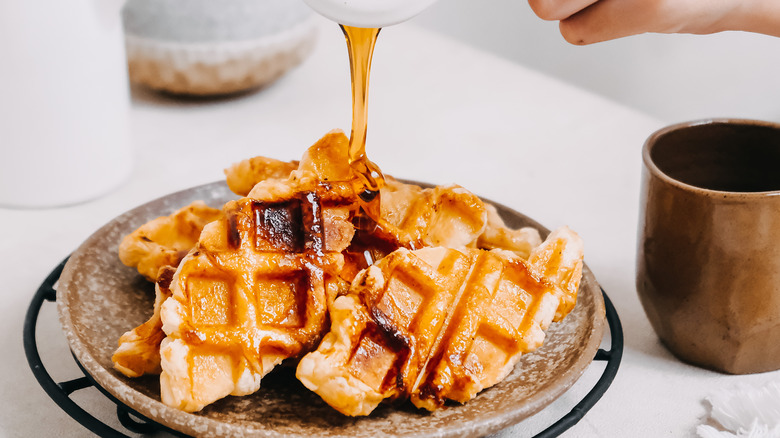 pouring maple syrup on waffles