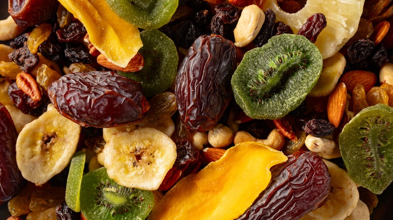 A close-up of various dried fruit, including dry bananas, dates, pineapple, kiwi, raisins, and mango with some cashews, pecans, and almonds