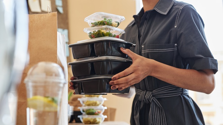 Person holding plastic takeout containers