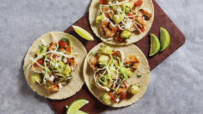 Three shrimp tacos lime wedges