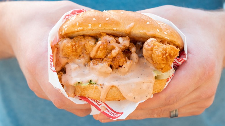 hands holding saucy chicken sandwich