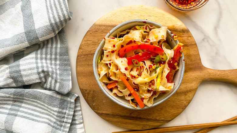 bowl of noodles with peppers on a board