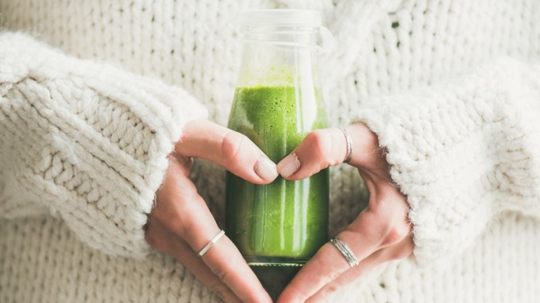 hands holding green smoothie