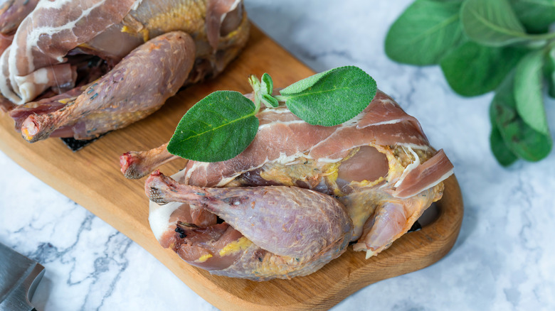 prosciutto-wrapped pheasant on wood board