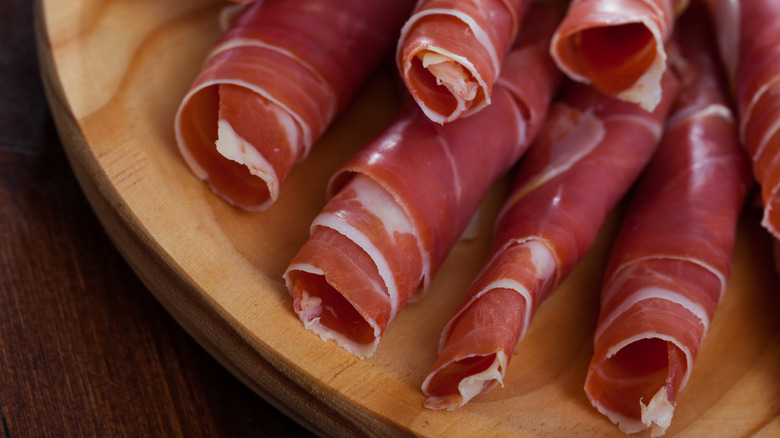 rolls of prosciutto di parma on cutting board