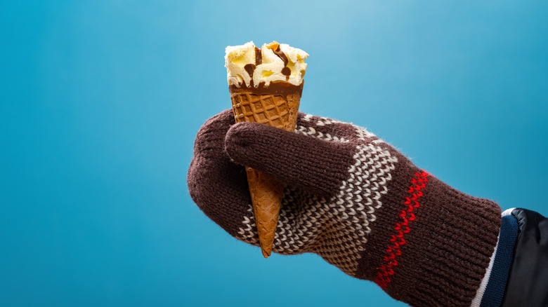 Hand with mitten holding ice cream cone