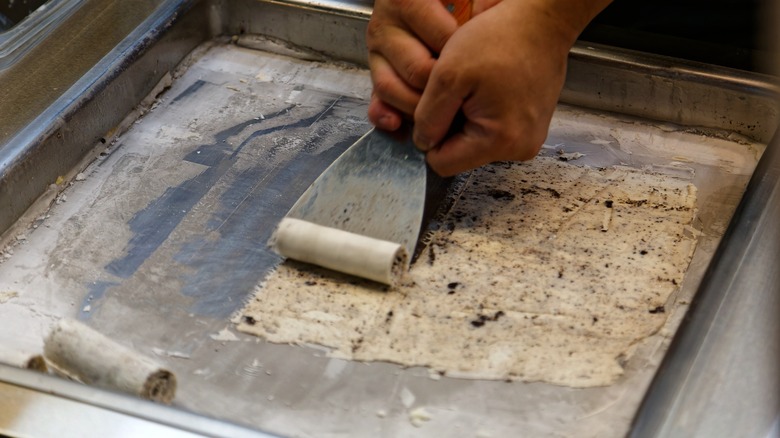 Hands rolling ice cream on pan