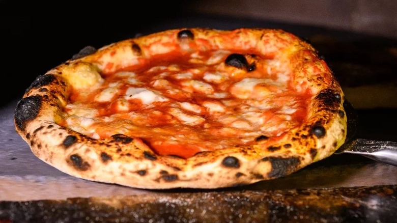 Pizza coming out of a brick oven