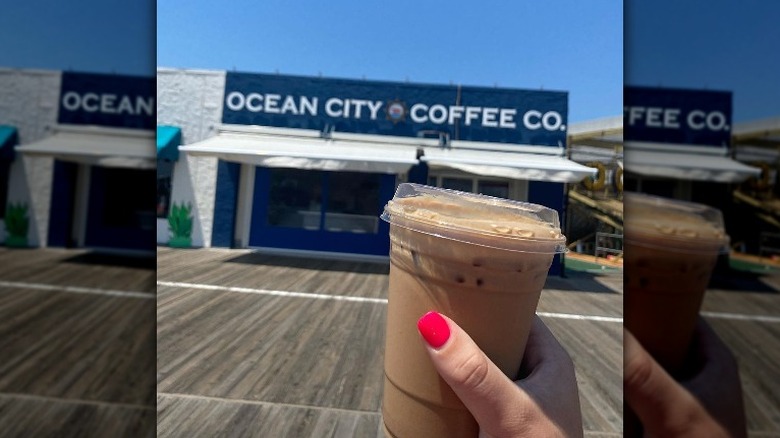 holding coffee on boardwalk