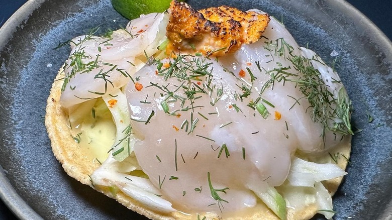 Tostada with half moon scallops and uni on black dish