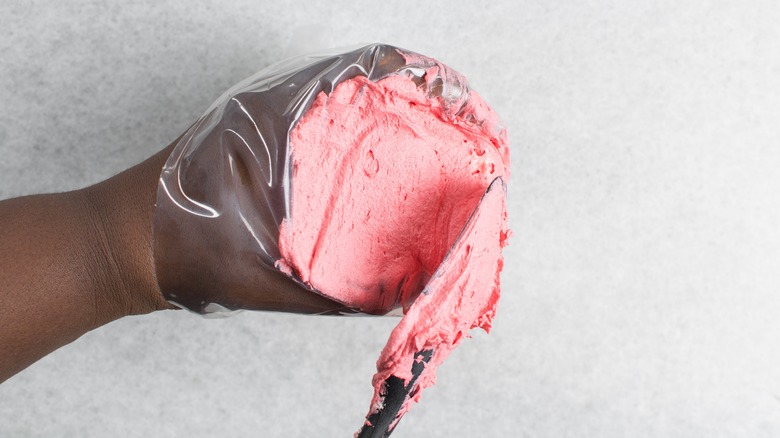 filling piping bag with pink frosting