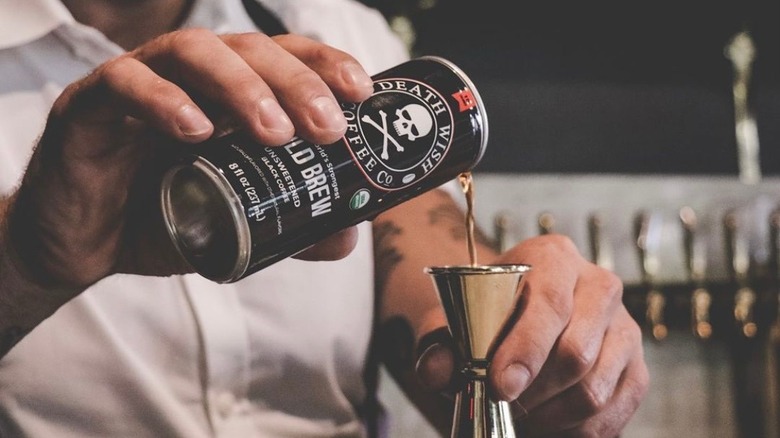 Person pouring cold brew can