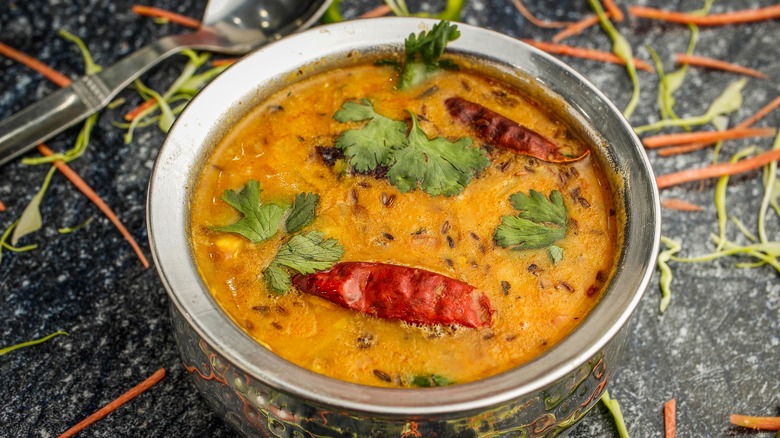 Dal tadka in a metal bowl with chilies and coriander