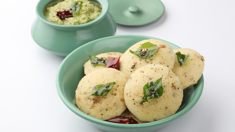 Bowl of steamed idli in a bowl and pot