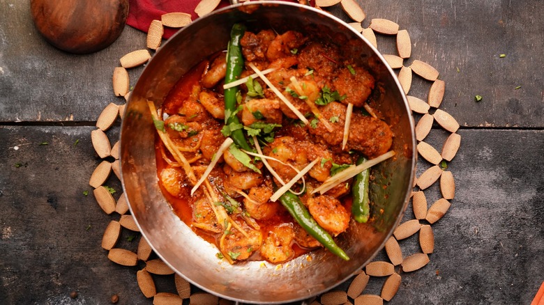 Chicken kadai in a copper dish with chilies