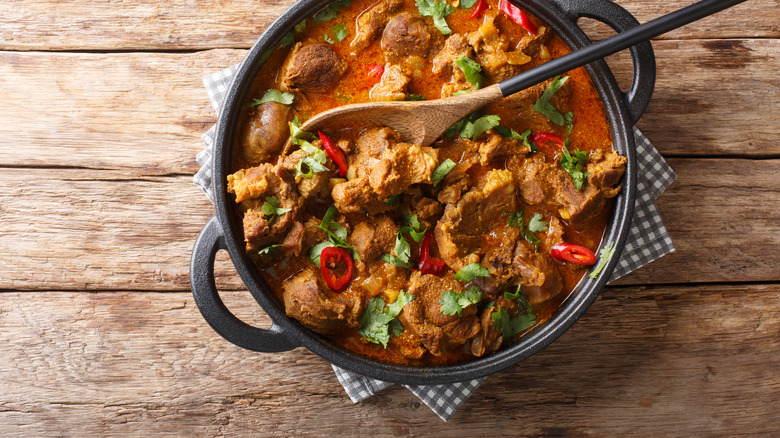 Rogan josh stew with a wooden spoon in a skillet