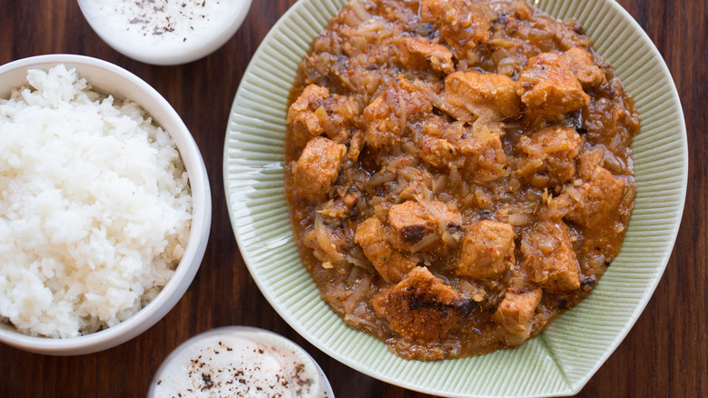 Pork vindaloo dish with rice on a wooden table