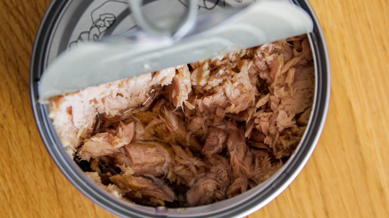 Opened can of tuna on a wooden table