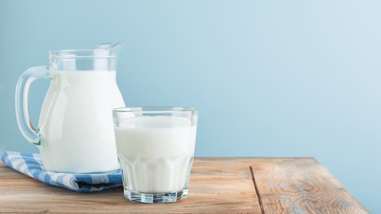 Glass and pitcher of milk on a wooden table