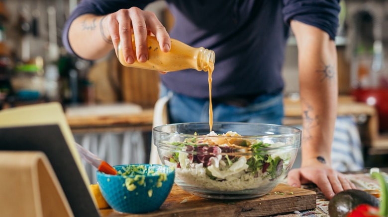 Man pouring dressing over salad