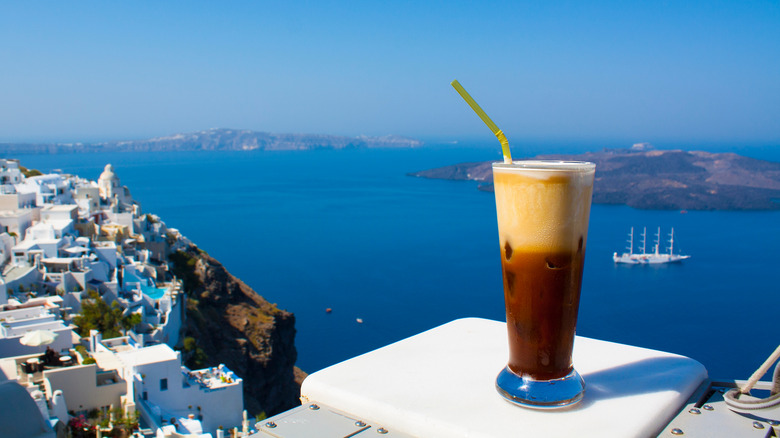 A glass of frappe on a table against the sea
