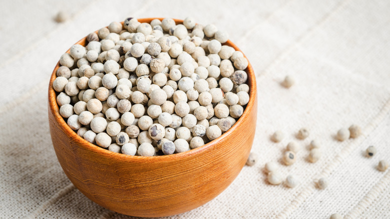 wooden bowl of white peppercorns