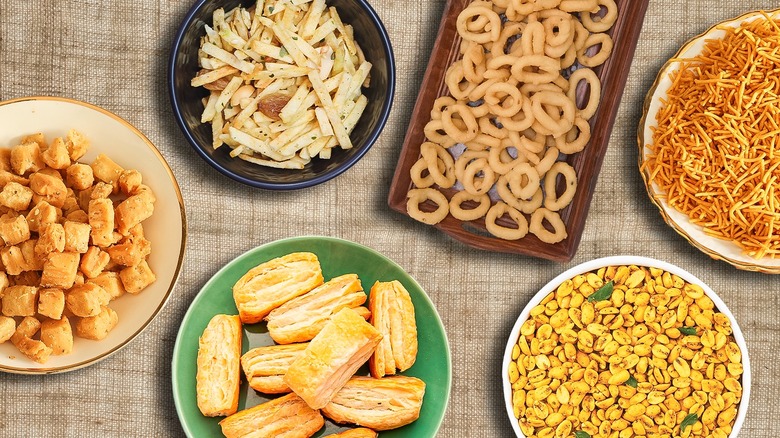 Top-down view of an assortment of salty Indian snacks on a tablecloth